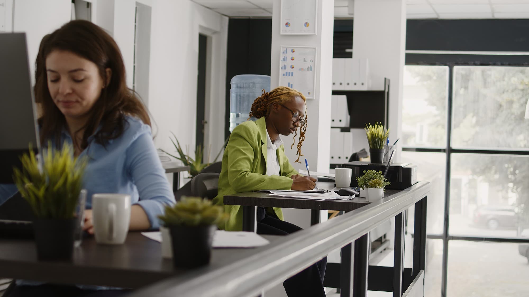 Colleagues working together at adjacent desks in an open office.