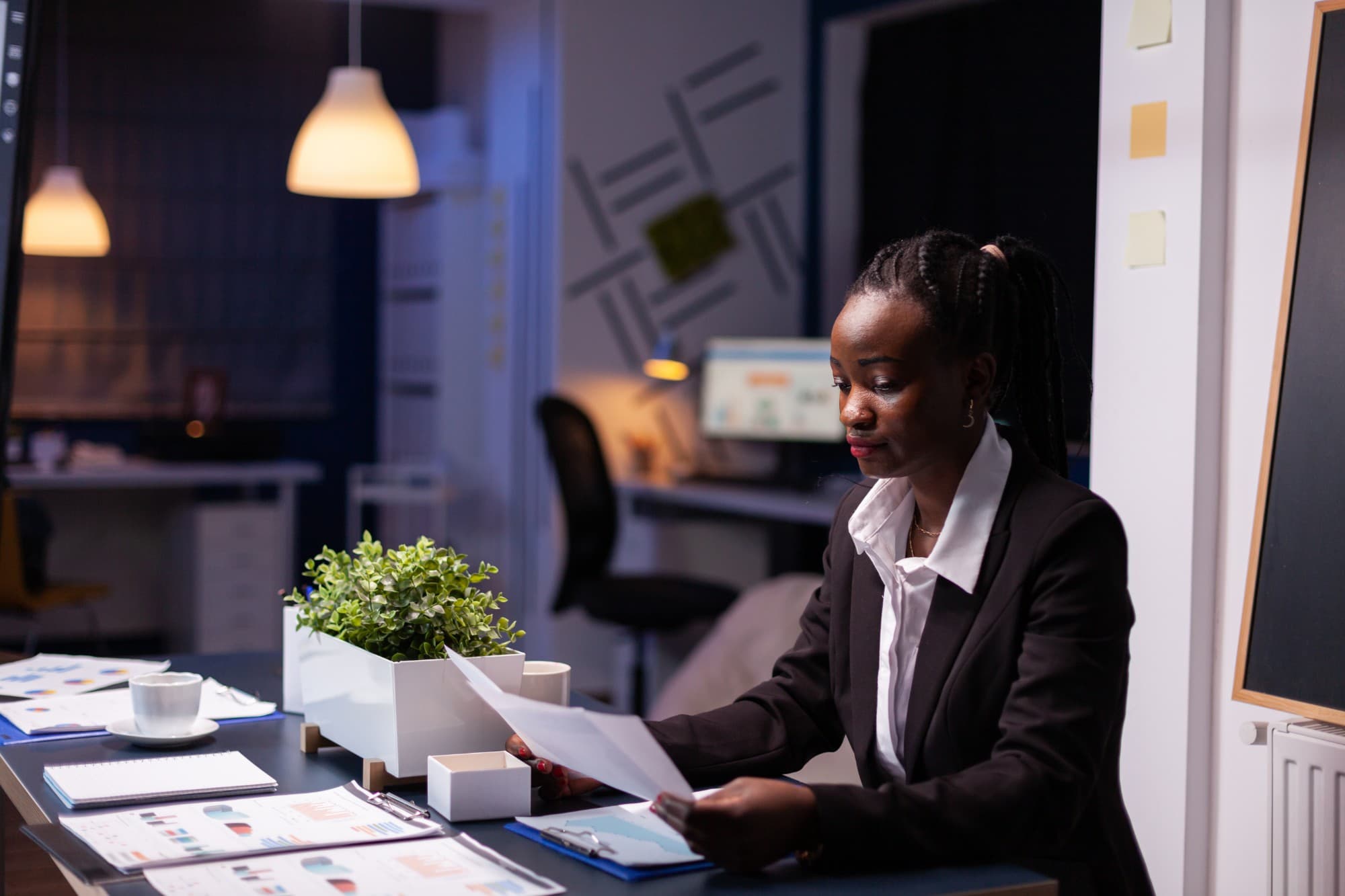 A professional reviewing documents at her desk in the evening.